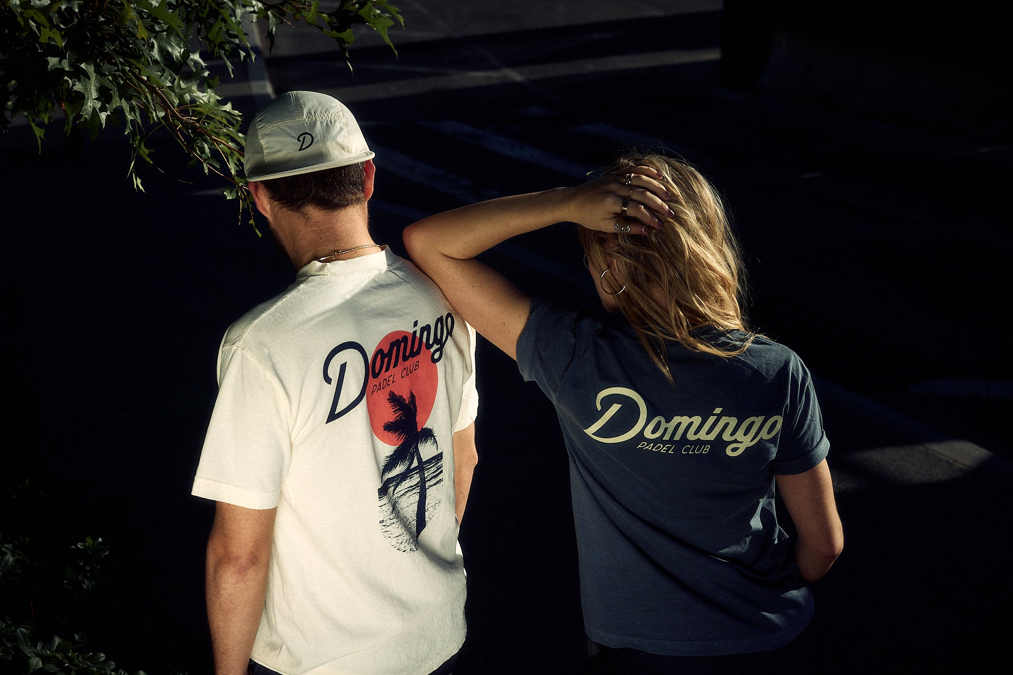 Two people wearing 'Domingo' branded shirts standing close to each other.